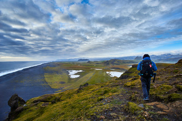 Fototapeta premium A man walking on top of Dyrholaey, Iceland