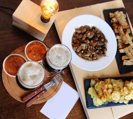 Beer and snacks. Lamp of Edison. Hipster still life. A wooden board. Potato chips, fries. Garlic toast. Plugs with wooden handles