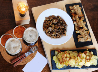 Beer and snacks. Lamp of Edison. Hipster still life. A wooden board. Potato chips, fries. Garlic toast. Plugs with wooden handles