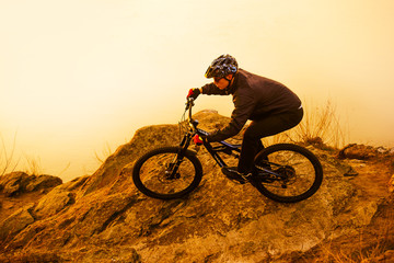 Obraz premium Enduro Cyclist Riding the Mountain Bike on the Rock. Extreme Sport Concept. Space for Text.