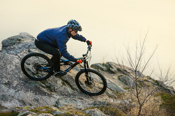 Fototapeta na wymiar Enduro Cyclist Riding the Mountain Bike on the Rock. Extreme Sport Concept. Space for Text.