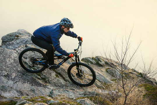 Enduro Cyclist Riding the Mountain Bike on the Rock. Extreme Sport Concept. Space for Text.