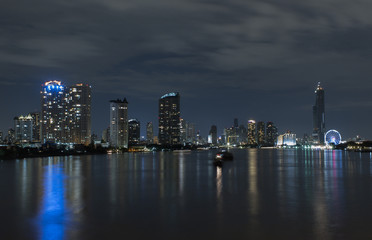 Night city river view with reflection in water.