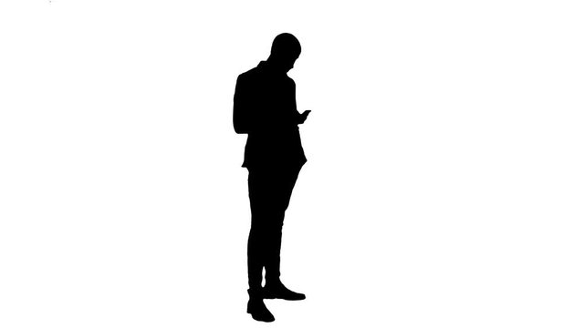 Silhouette Business man walks in checking up his phone