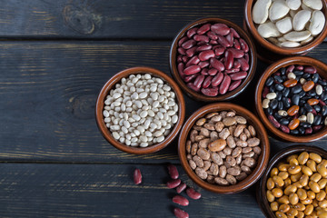 Obraz na płótnie Canvas Assortment of beans on wooden background. Soybean, red kidney bean, black bean,white bean, red bean and brown pinto beans