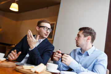 Two young analysts co-working and interacting in cafe