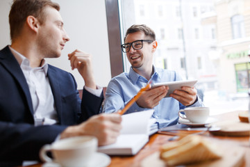 Happy young man looking at his colleague during dsicussion of sales