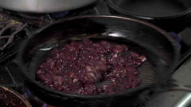 Red kidney beans frying in a pan, close-up.