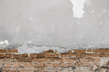 Grey cracked concrete wall with bricks