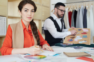 Young fashion designer and her colleague working in studio