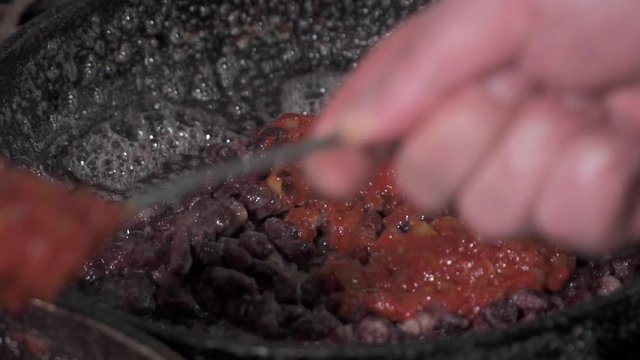Red kidney beans frying in red sauce in a pan, slow motion