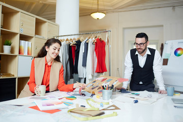 Happy designer choosing fabric samples for new collection of clothes