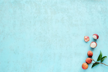 Naklejka na ściany i meble Bunch of fresh lychee (litchi, liche) on a blue background. Space for text. Top view.