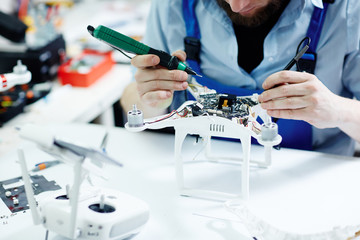 Closeup shot of unrecognizable man  testing electric current in circuit board of disassembled drone...