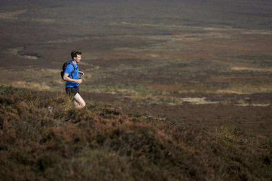 Male runner running down moorland