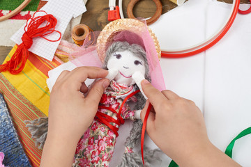 child hand making dress for handmade doll, learn to sewing