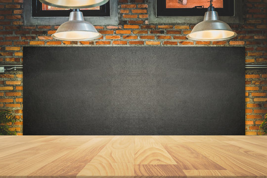 wood frame blackboard backgrounds with wood table top in the kitchen for product display , menu board with lamp and light on wall in restaurant
