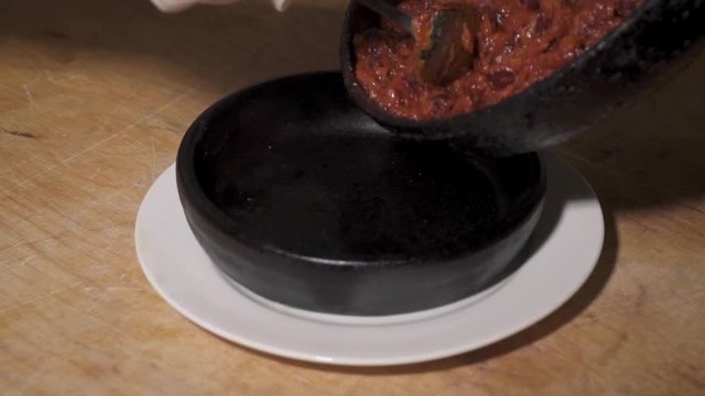 Chef serving frying bens in tomato sauce, slow motion