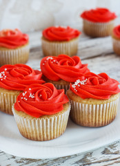 Vanilla cupcakes decorated with a red rose from a cream on a white background