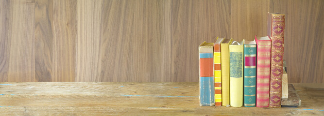 row of books on wooden background, panorama format, good copy space