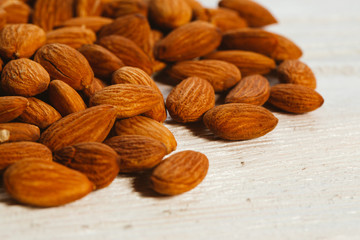 handful of almonds on a white wooden background