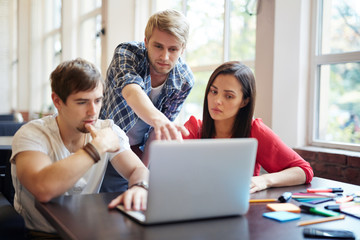 Three business people looking at data on laptop screen