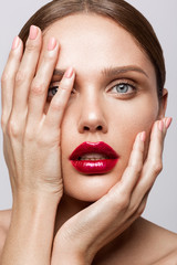 Beautiful young model with red lips and nude manicure