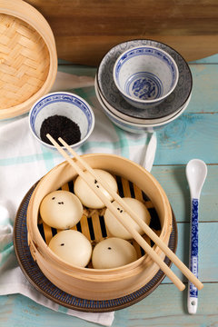 Bapao, steamed bun with savory, meat filling. Bamboo steamer, sesam, bowls.