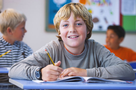 Portrait of boy in classroom, sitting at desk, doing classwork