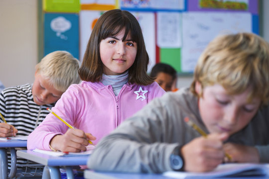 Portrait of girl in classroom, sitting at desk, doing classwork
