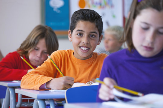 Portrait of boy in classroom, sitting at desk, doing classwork
