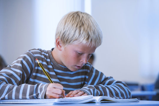 Boy in classroom, sitting at desk, doing classwork