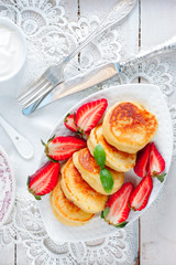 Breakfast with homemade yeast pancakes, honey and strawberries, top view