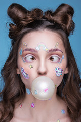 Beautiful fashion girl with funny professional makeup and emoji stickers glued on the face.