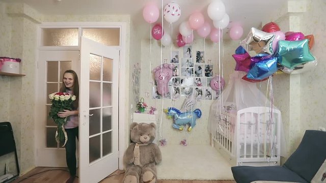 Young mother walks into the room with a surprise and smiles.