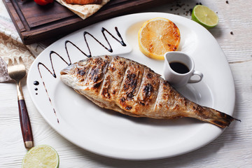 Baked fish dorado on a plate lemon balsamic still life