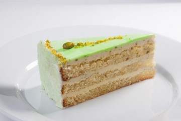 Pistachio cake slice on a plate close-up isolated white background