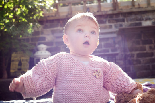 Surprised baby girl with open mouth in garden