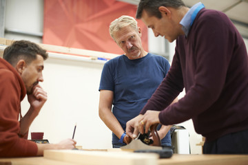 Man explaining carpentry technique in carpentry class