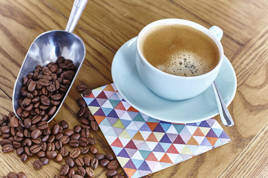 Still life of cup of coffee and scoop with coffee beans