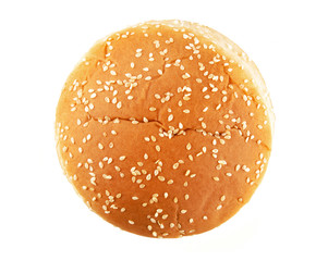 Hamburger bun with sesame seeds isolated on white background. Top view.