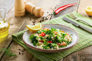 Healthy salad made of couscous, broccoli, tomato, pepper, onion and dill on a table. Traditional Moroccan food for healthy meal.