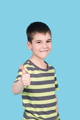 portrait of happy smiling teenage boy showing thumbs up gesture, isolated over blue background