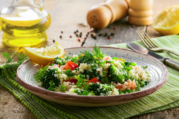 Traditional Moroccan couscous with broccoli, tomato and other vegetables on a plate. Eastern meal for healthy lunch on a table.