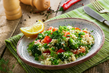 Delicious healthy meal made of couscous, broccoli and other vegetables on a rustic wooden table. Traditional eastern food.