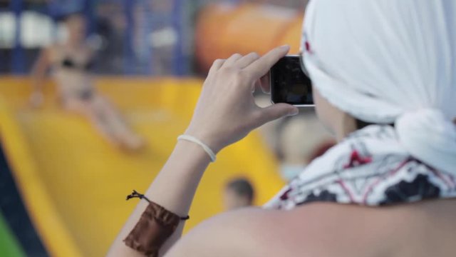 Woman taking pictures for her family with her smartphone at waterpark