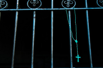 Blue rosary beads dangling from old iron railings
