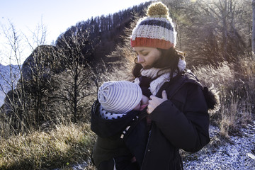 Mature woman breastfeeding  baby son on mountainside track
