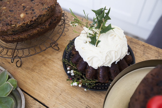 Cakes on kitchen counter, one decorated with icing and leaves