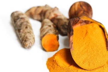 Turmeric powder in a wooden scoop isolated on white, selective focus